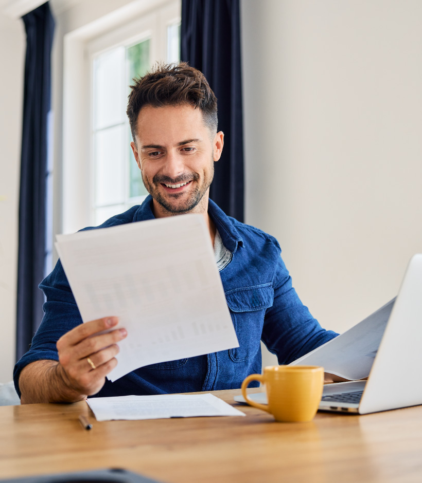 person reviewing paperwork by laptop