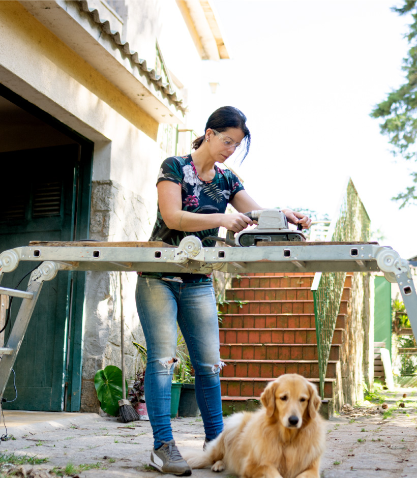 women sanding something with dog nearby