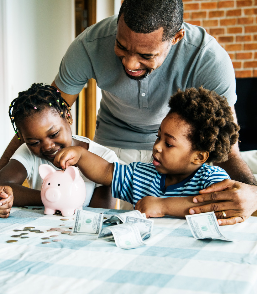 two kids and their dad counting money in a piggy bank